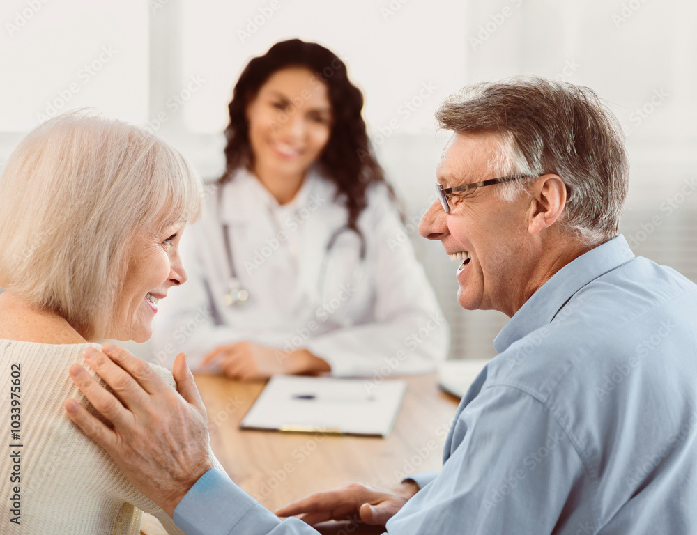 Fototapeta premium Heathcare Concept. Back view of happy senior husband comforting his wife during consultation with mexican doctor