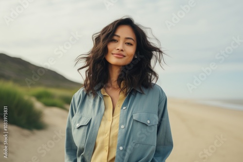 Portrait of a satisfied asian woman in her 20s sporting a versatile denim shirt on serene dune landscape background