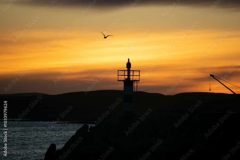 Fototapeta premium Aatardecer en el Puerto de Camarones, en la Patagonia Argentina, provincia de Chubut, donde se puede apreciar el característico faro. 