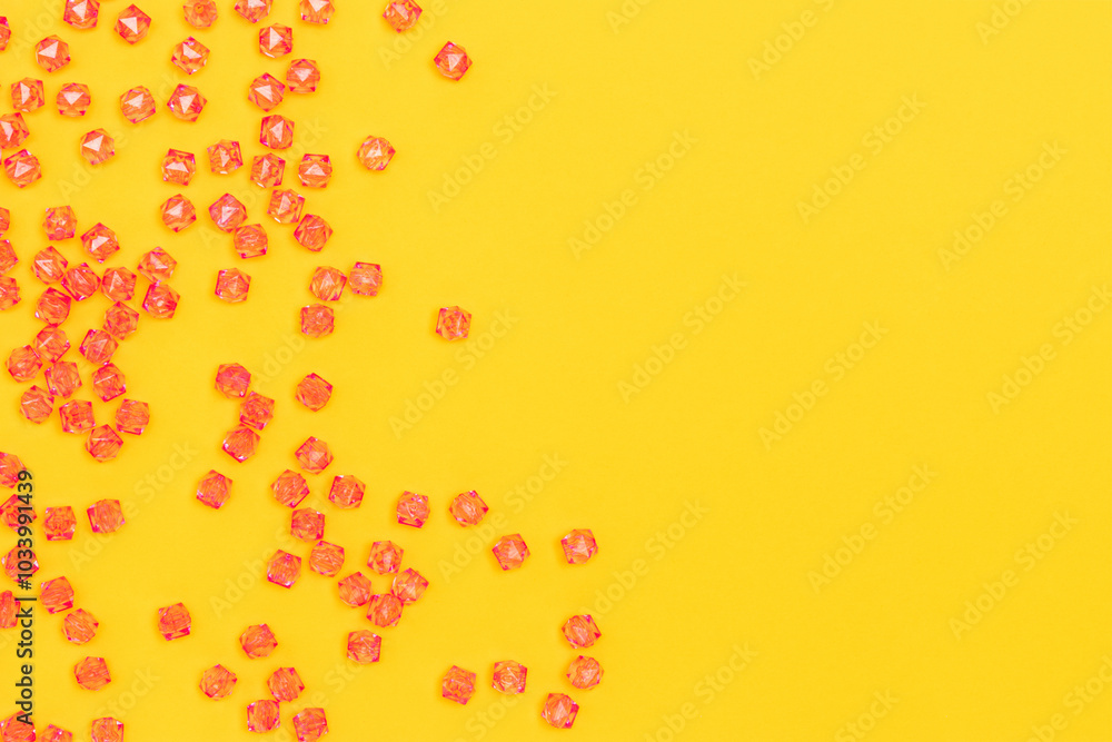 Pink acrylic beads scattered on a yellow background with place for text. Pink acrylic beads scattered on a yellow background with place for text.