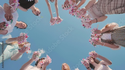 Friends of school children toss colorful confetti while standing in a circle.