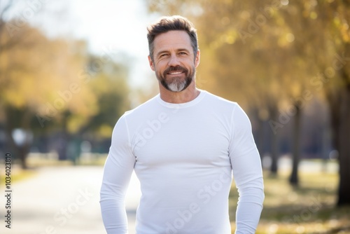 Portrait of a content man in his 40s sporting a long-sleeved thermal undershirt over bright and cheerful park background