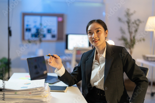 Focused asian businesswoman works late in a modern office, planning strategies with confidence and determination