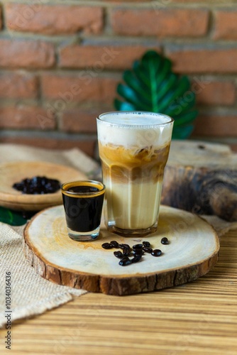 Glass of cappuccino with foam and espresso in natural background and wood elements