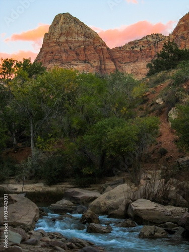 The majestic peak of the Watchman towering over the fast flowing Virgin River in Zion Canyon, in Utah, at dusk. photo