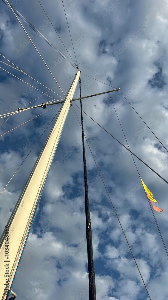 Fototapeta premium Navegando en Velero con bandera de Colombia al atardecer con fondo de cielo y nubes