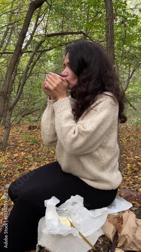 Woman enjoying hot tea in forest. Relaxing woman drinking tea in nature