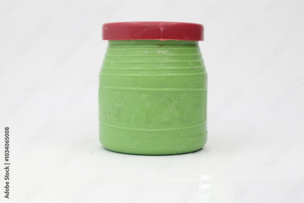 A small, green plastic container with a red lid. The container has a ribbed texture and is filled with white glue. It is a common type of glue used for paper crafts and other small projects. A small, green plastic container with a red lid. The container has a ribbed texture and is filled with white glue. It is a common type of glue used for paper crafts and other small projects.