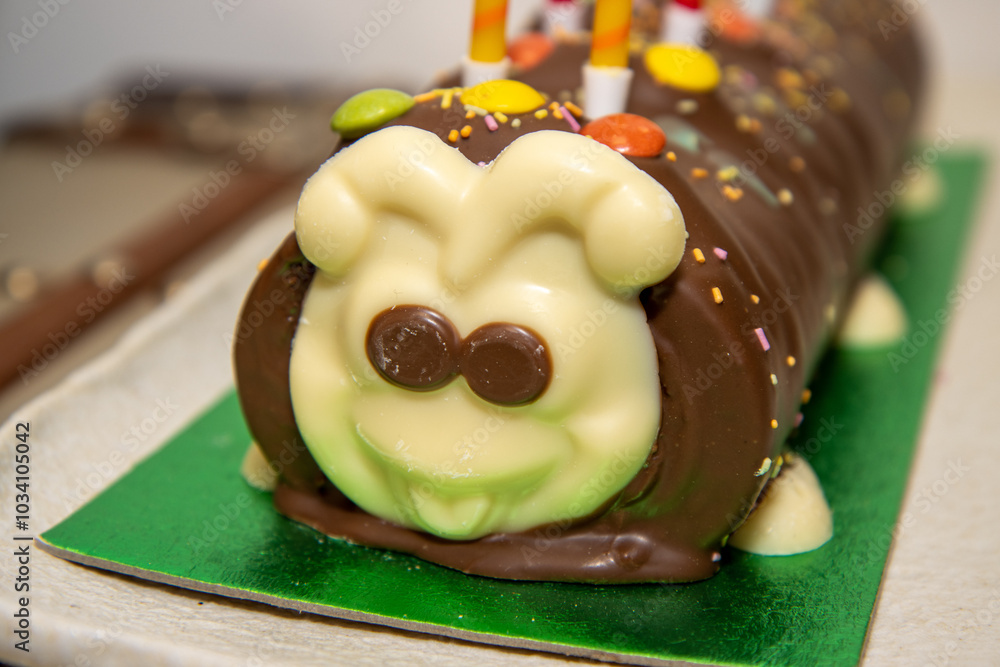 A children's birthday cake in the shape of a caterpillar covered in chocolate
