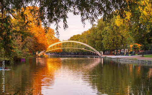 Sunrise lighting up the autumn foliage on the trees and Suspension Bridge over the River Great Ouse on the Embankment in Bedford, England photo