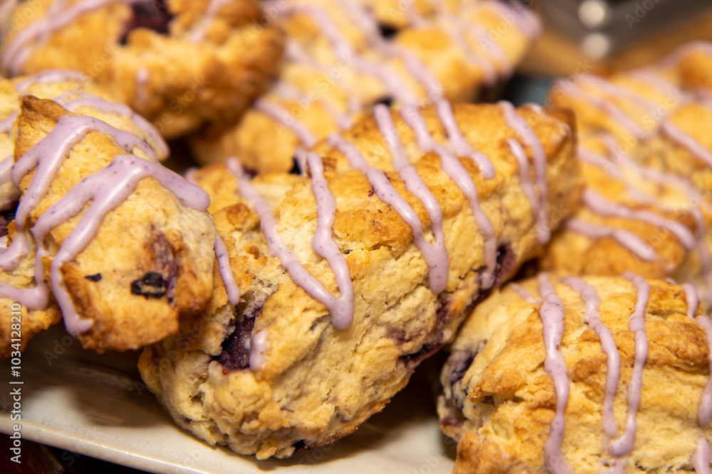 A delicious plate of pumpkin spice scones covered in pink icing on a kitchen work top A delicious plate of pumpkin spice scones covered in pink icing on a kitchen work top