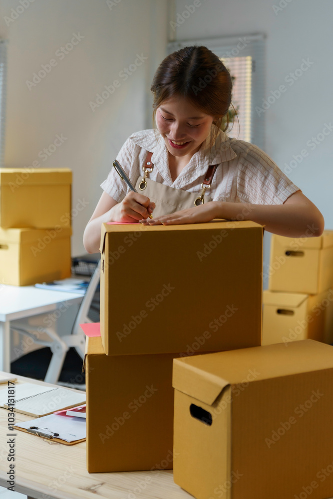 Young asian sme business woman working in a home office, she is preparing parcel boxes for packing and sending to customers Young asian sme business woman working in a home office, she is preparing parcel boxes for packing and sending to customers