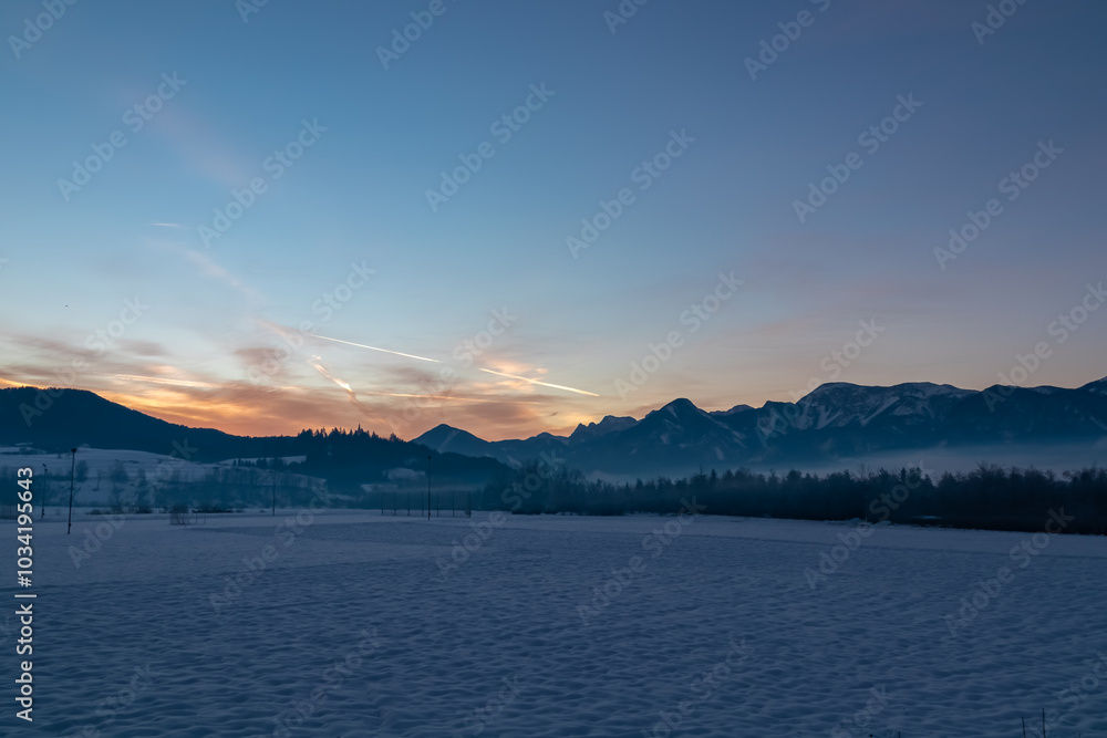 Snow covered field with scenic sunrise view of majestic snow-capped mountain range in Karawanks seen from Rosental, Carinthia, Austria. Peaceful alpine landscape. Tranquil winter scene Austrian Alps Snow covered field with scenic sunrise view of majestic snow-capped mountain range in Karawanks seen from Rosental, Carinthia, Austria. Peaceful alpine landscape. Tranquil winter scene Austrian Alps