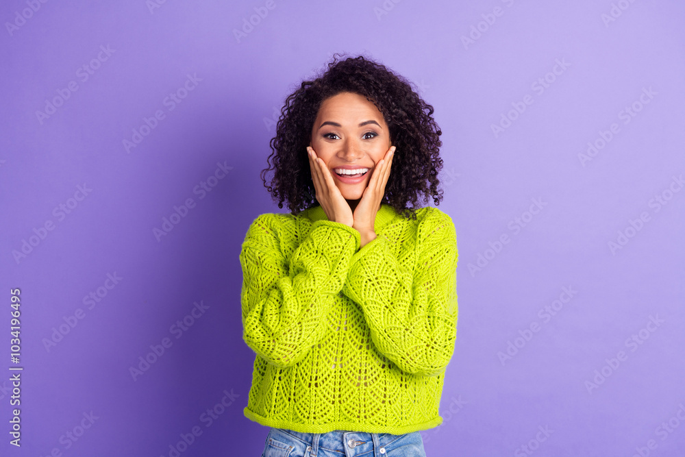 Portrait photo of wavy haired student cute woman in green trendy knitted sweater touch cheeks surprised isolated on violet color background Portrait photo of wavy haired student cute woman in green trendy knitted sweater touch cheeks surprised isolated on violet color background
