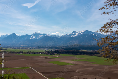 Panoramic view of snow-capped mountain peaks of Karawanks range seen from zoo Tierpark Rosegg, Carinthia, Austria. Tranquil calm scene on sunny day in Rosental Valley, Austrian Alps. Trees in spring photo