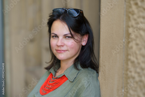 Beautiful dark-haired European woman in her thirties poses for a portrait photo in a khaki linen shirt and coral beads. Concept of natural female beauty photo