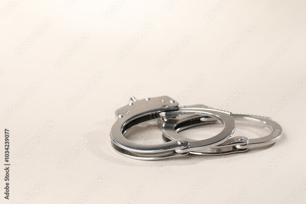 Metal chain handcuffs on light grey background, closeup. Space for text Metal chain handcuffs on light grey background, closeup. Space for text