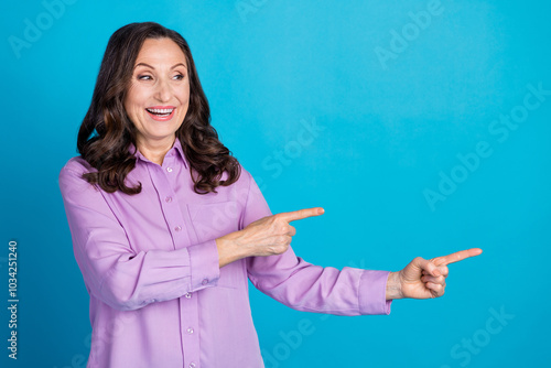 Photo of cheerful pretty lady dressed puple blouse showing looking empty space isolated blue color background