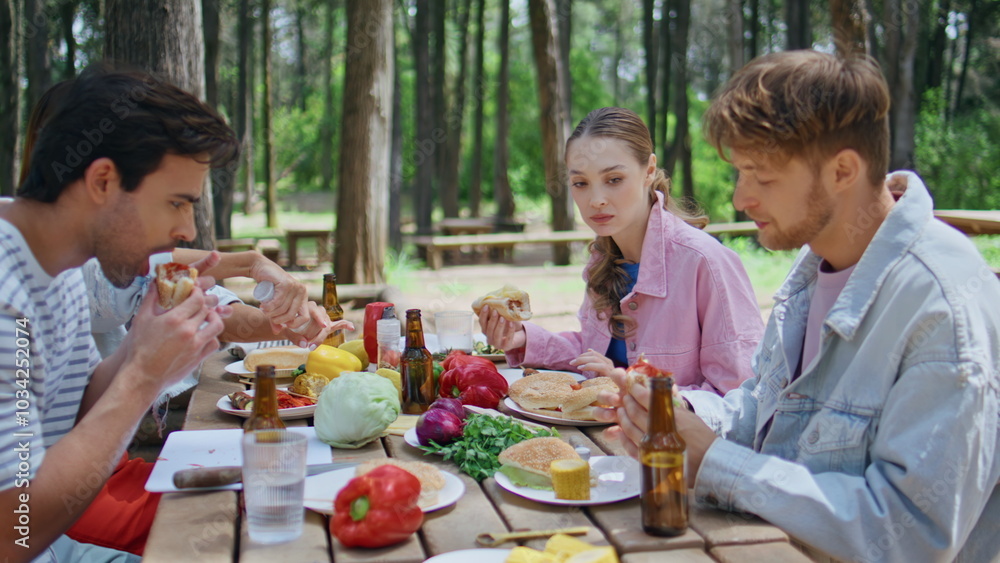 Laughing group eating picnic table in summer forest closeup. Relaxed youngsters Laughing group eating picnic table in summer forest closeup. Relaxed youngsters