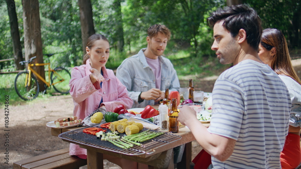 Friendly group having picnic in sunny forest closeup. Two young couple talking Friendly group having picnic in sunny forest closeup. Two young couple talking