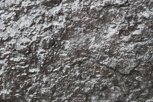 Wet rock background. Grunge texture of shiny stone. Steel-like appearance. Scratched and rough surface. Industrial black background. Dark stone and rock texture.