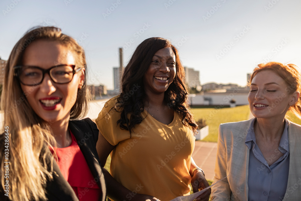 Obraz premium Three businesswomen smiling and sharing ideas outdoors