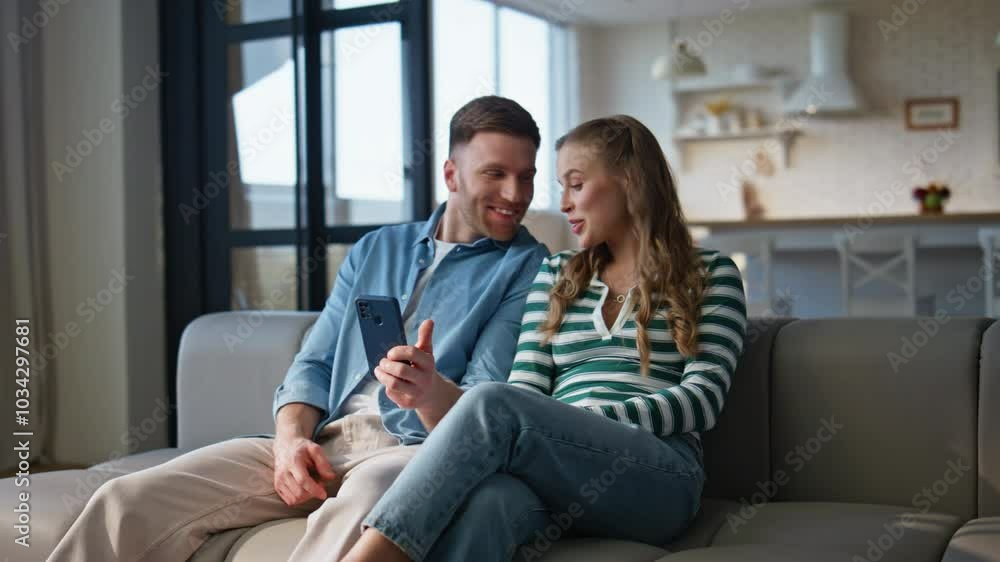 Married couple watching smartphone at living room closeup. Husband bonding wife Married couple watching smartphone at living room closeup. Husband bonding wife