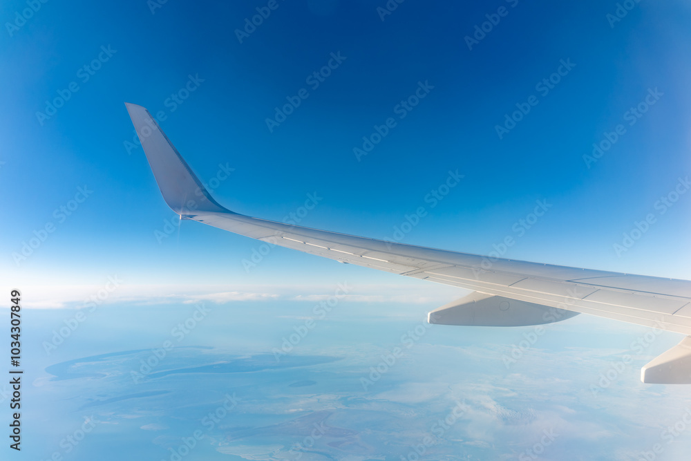 View from the airplane window at a beautiful blue clear sky, earth, sea and the airplane wing View from the airplane window at a beautiful blue clear sky, earth, sea and the airplane wing