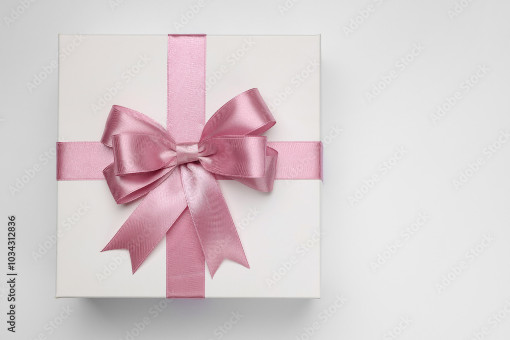 Gift box with pink bow on light grey background, top view. Space for text Gift box with pink bow on light grey background, top view. Space for text