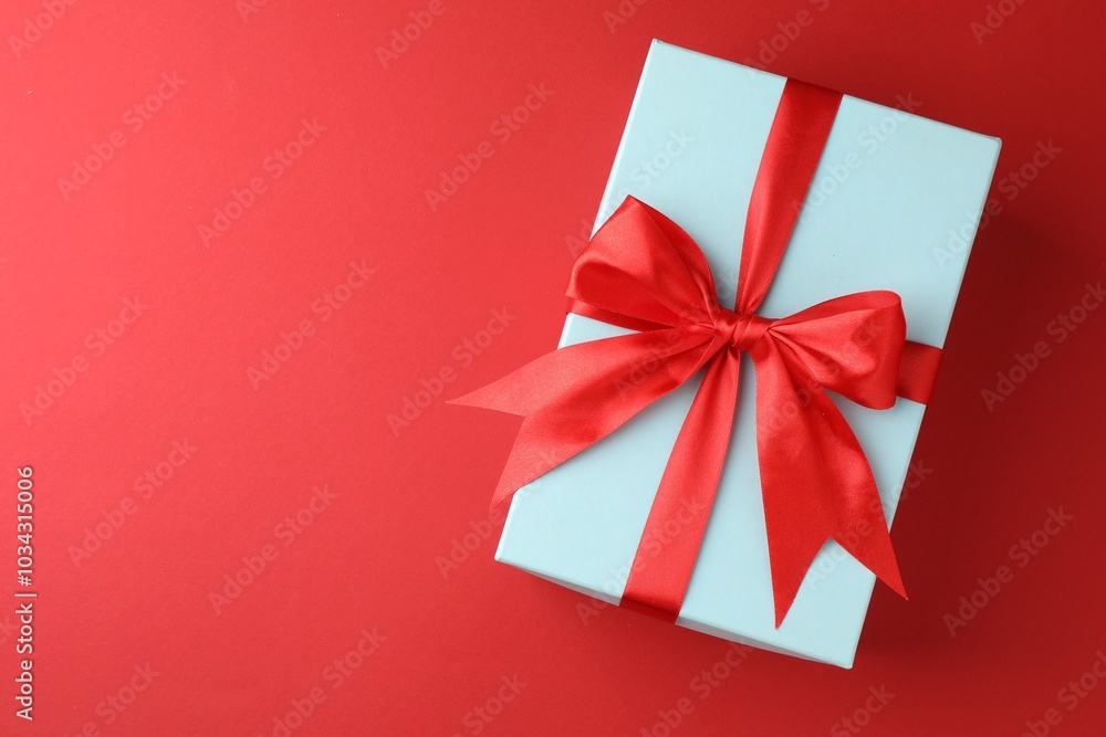 Gift box with bow on red background, top view. Space for text Gift box with bow on red background, top view. Space for text