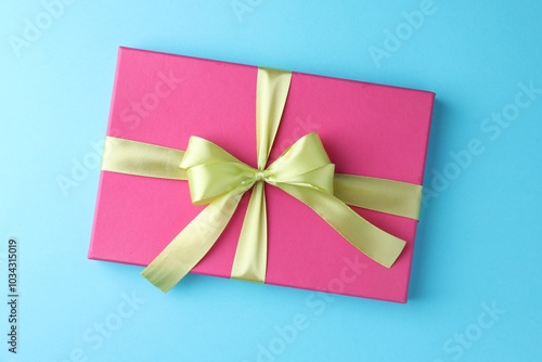 Gift box with bow on light blue background, top view