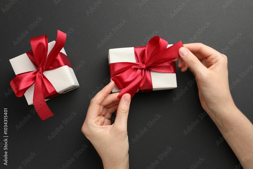 Woman opening gift box on black background, top view Woman opening gift box on black background, top view