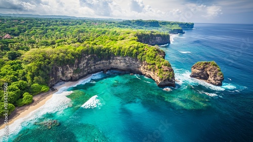 An aerial view of Diamond Beach, Bali, showcasing vibrant turquoise waters crashing against the rugged cliffs, with a lush green outcrop jutting into the ocean and a small pristine beach nestled betwe photo