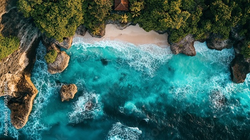 An aerial view of Diamond Beach, Bali, showcasing vibrant turquoise waters crashing against the rugged cliffs, with a lush green outcrop jutting into the ocean and a small pristine beach nestled betwe photo