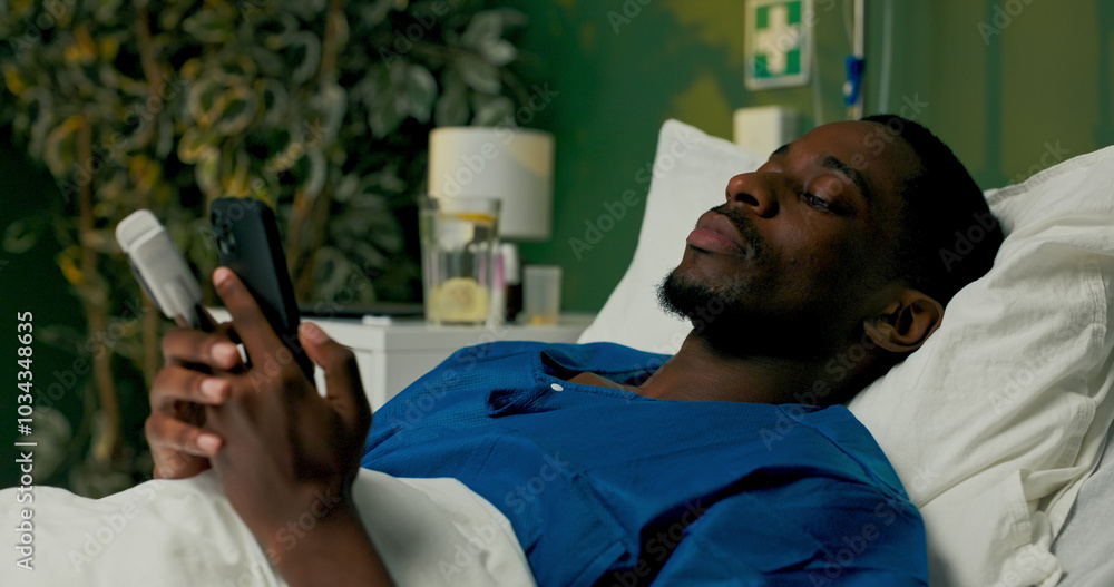 Guy in the hospital bed, chatting on his phone, updating friends about his day or sharing funny memes to lift spirits. Guy in the hospital bed, chatting on his phone, updating friends about his day or sharing funny memes to lift spirits.