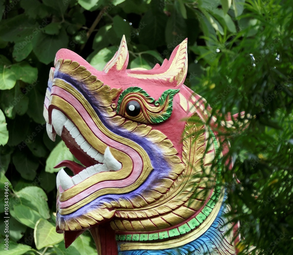 Close-up of a colorful, traditional dragon sculpture with lush green foliage in the background Close-up of a colorful, traditional dragon sculpture with lush green foliage in the background