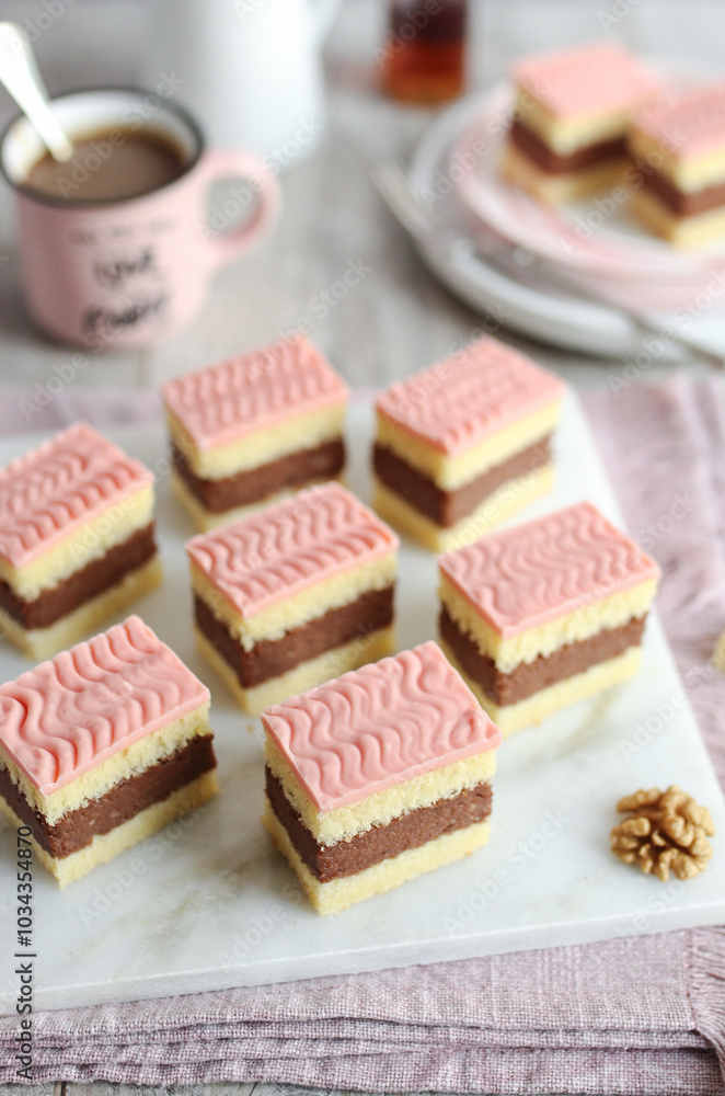 Rum punch cake with rum and soft layers of cake with pink glaze on top. Cup of coffee and a bottle of rum in background. Rum punch cake with rum and soft layers of cake with pink glaze on top. Cup of coffee and a bottle of rum in background.