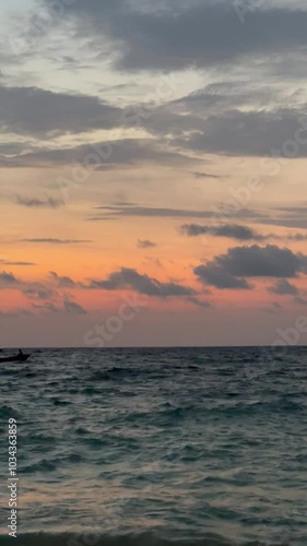 Bote navegando en el mar caribe con cielo naranja al atardecer