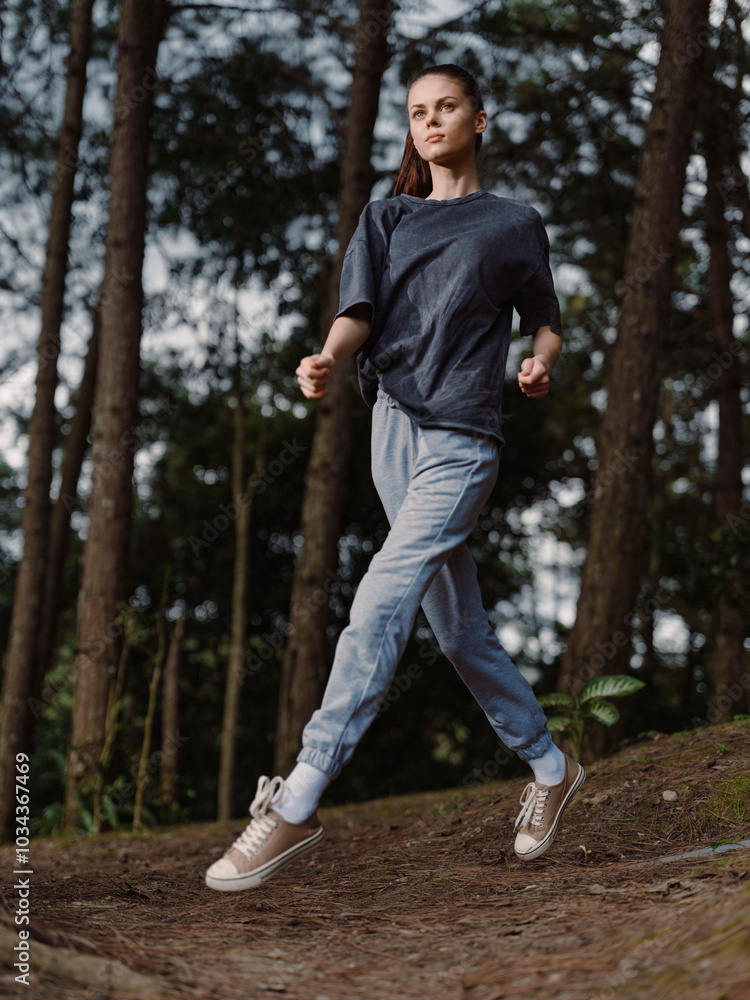 Young woman confidently walking through a forest, dressed in casual athletic clothing, exuding a sense of freedom and connection with nature Young woman confidently walking through a forest, dressed in casual athletic clothing, exuding a sense of freedom and connection with nature