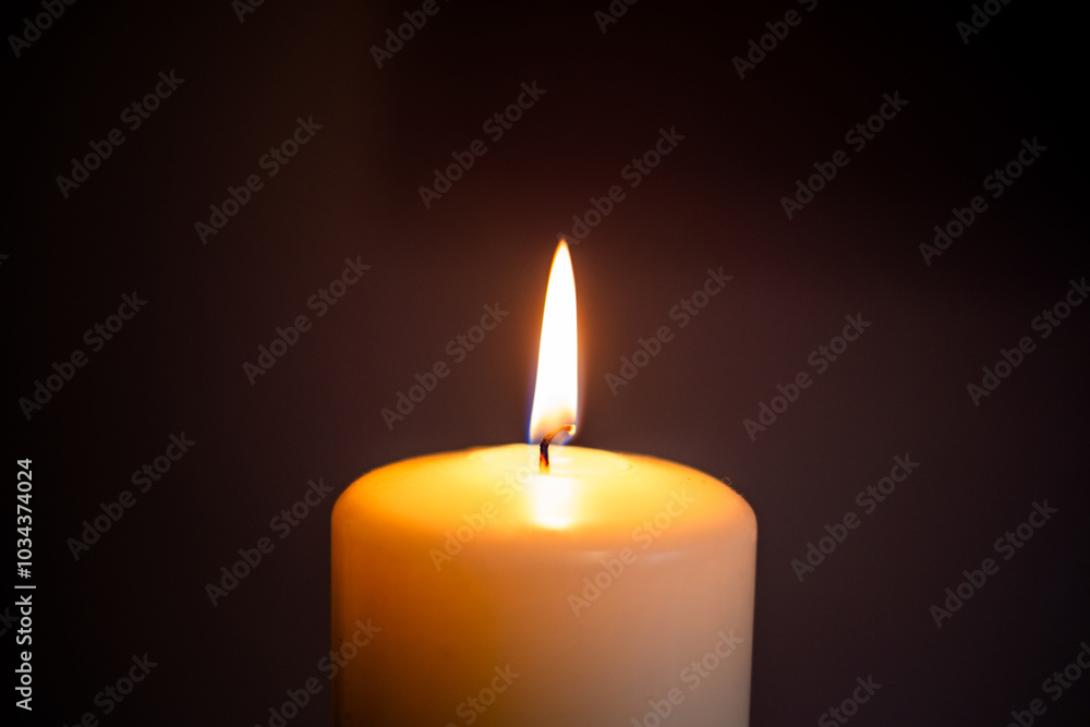 A single candle flame illuminating darkness in a serene indoor setting during evening hours. Baccground for funeral, obituary, in memoriam with copy space A single candle flame illuminating darkness in a serene indoor setting during evening hours. Baccground for funeral, obituary, in memoriam with copy space