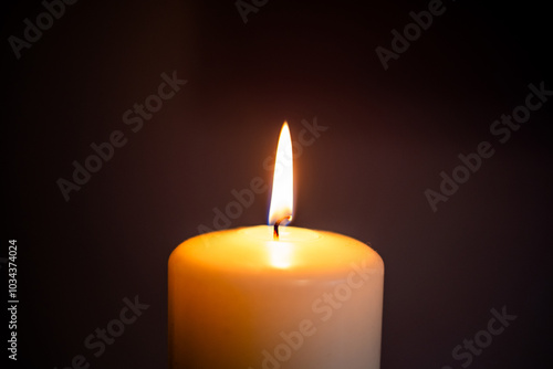 Fotografia A single candle flame illuminating darkness in a serene indoor setting during evening hours