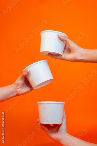 Hands holding white packaging recipients on colored background