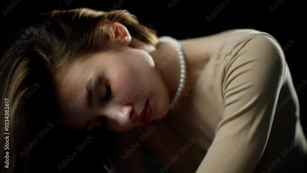 Young woman in a beige leotard and pearl necklace poses elegantly against a black backdrop, displaying fluid movements and captivating expressions Young woman in a beige leotard and pearl necklace poses elegantly against a black backdrop, displaying fluid movements and captivating expressions