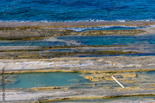 A tranquil coastal landscape featuring exposed rock formations and clear blue waters at low tide under a bright sun photo