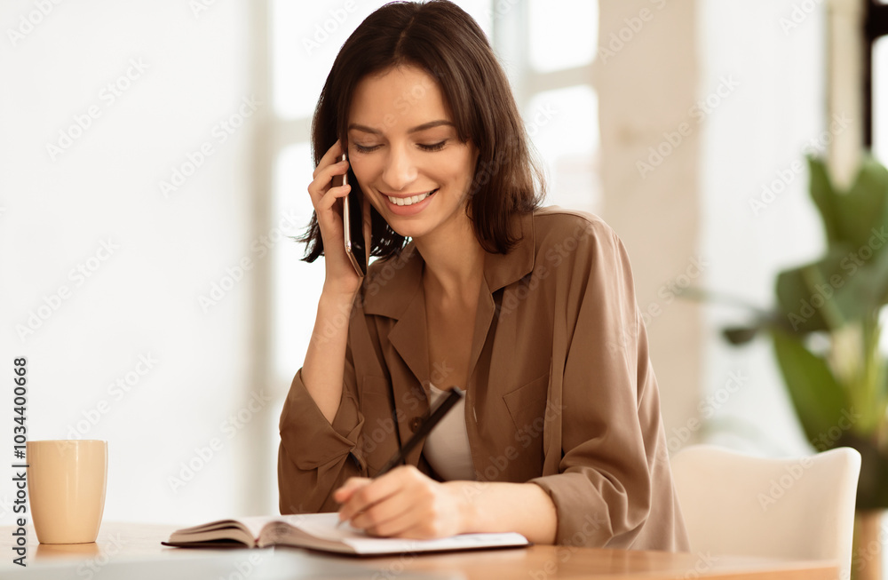 Taking Notes. Millennial businesswoman talking on mobile phone and writing ideas in a notebook, copyspace Taking Notes. Millennial businesswoman talking on mobile phone and writing ideas in a notebook, copyspace