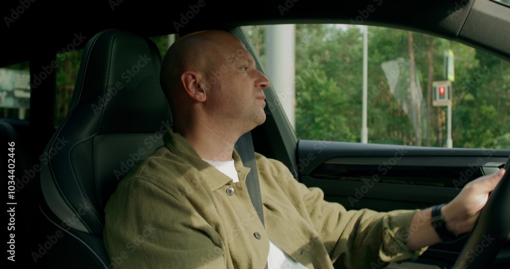 A man wearing a seat belt drives a car with a calm look. View from the car interior. Summer day A man wearing a seat belt drives a car with a calm look. View from the car interior. Summer day