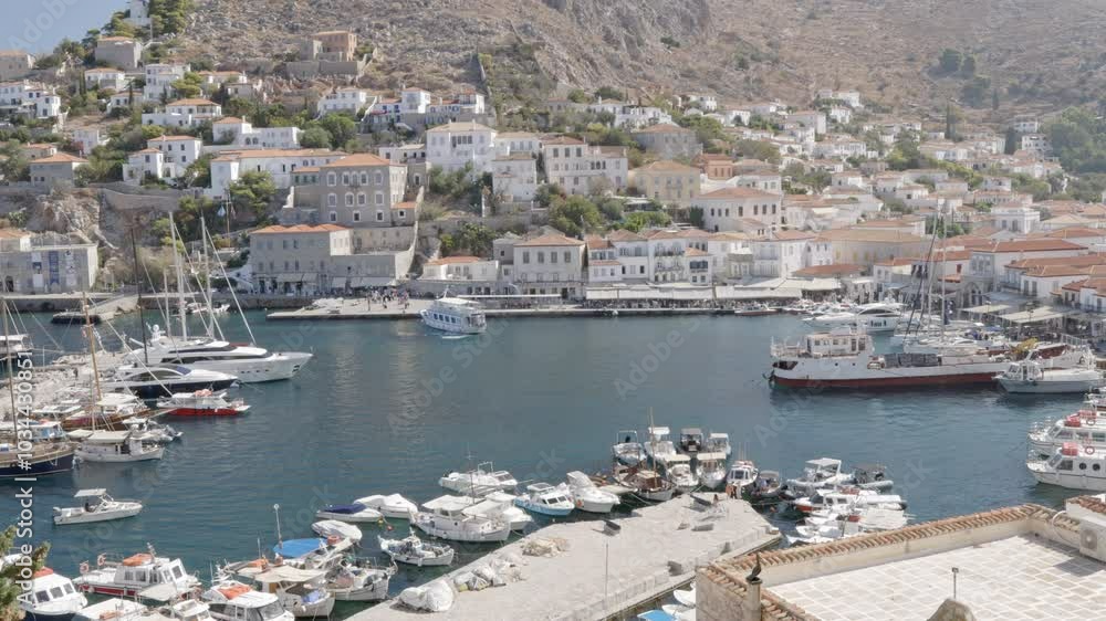 A picturesque view of Hydra port during a sunny summer day, showcasing the vibrant atmosphere with boats and charming traditional houses. A picturesque view of Hydra port during a sunny summer day, showcasing the vibrant atmosphere with boats and charming traditional houses.