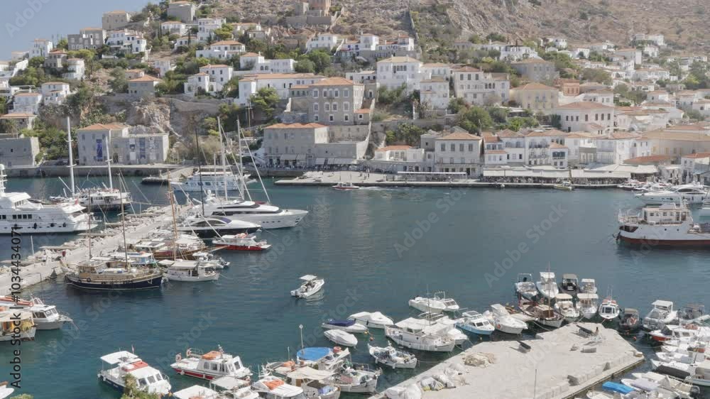 A picturesque view of Hydra port during a sunny summer day, showcasing the vibrant atmosphere with boats and charming traditional houses. A picturesque view of Hydra port during a sunny summer day, showcasing the vibrant atmosphere with boats and charming traditional houses.
