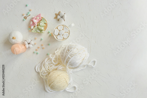 A delicate arrangement of yarn balls, pastel colored beads, and crafting materials on a light textured surface.