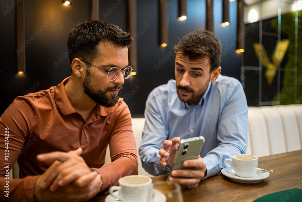 Two colleagues hanging out at the coffee shop. Working together on phone. Two colleagues hanging out at the coffee shop. Working together on phone.